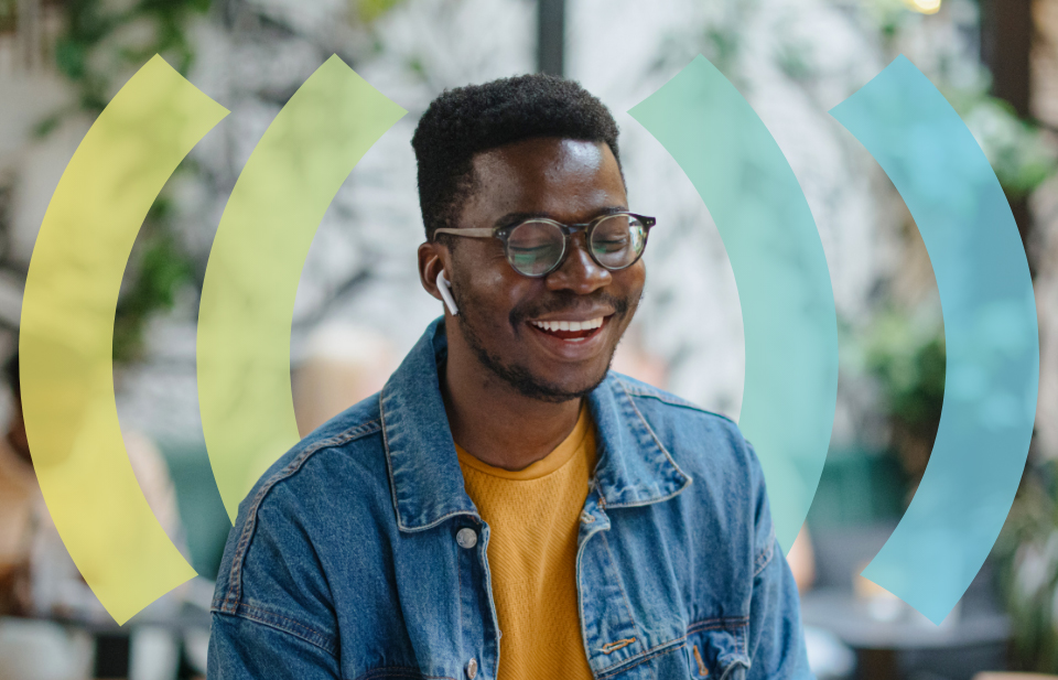 Man smiling while wearing earphones and a denim jacket