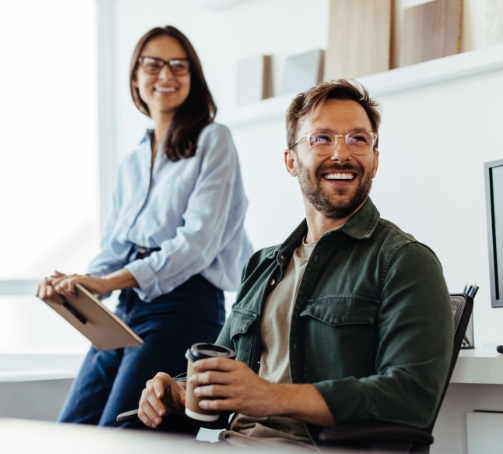 Colleagues smiling at work with tablet and coffee mug