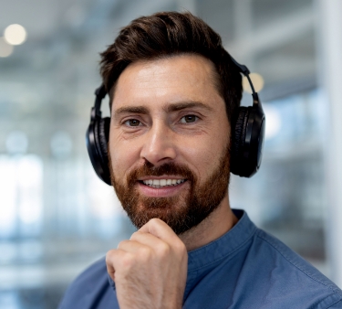 Man smiling with headphones in a modern office setting
